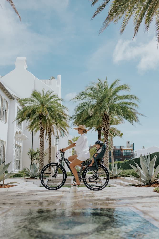 Woman with child rides an Aventon electric bicycle in suburban neighborhood