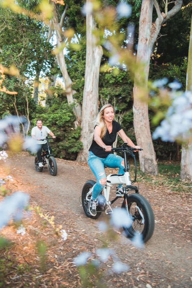 Couple riding Aventon electric bicycles on a woodland trail